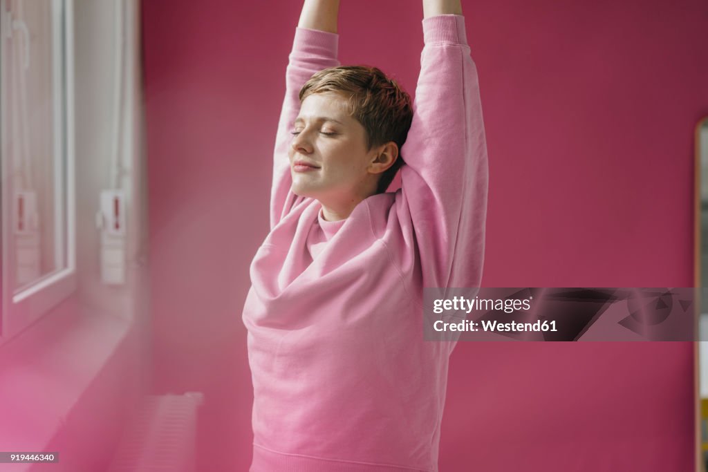 Woman in pink stretching at the window