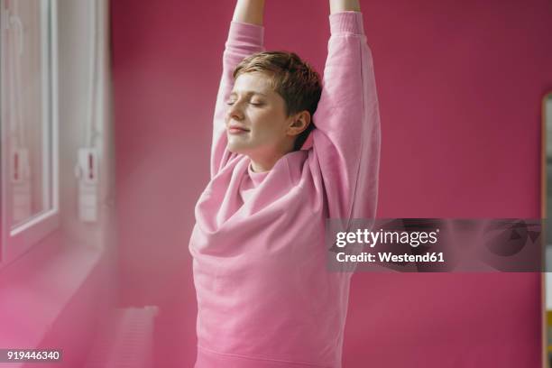 woman in pink stretching at the window - oberkörperaufnahme stock-fotos und bilder