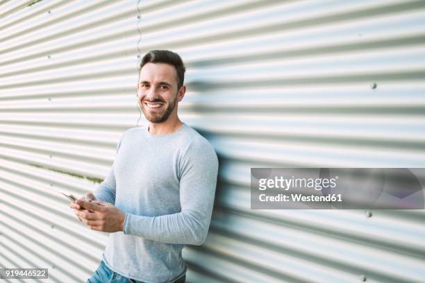 portrait of laughing man with smartphone - long sleeved stock-fotos und bilder