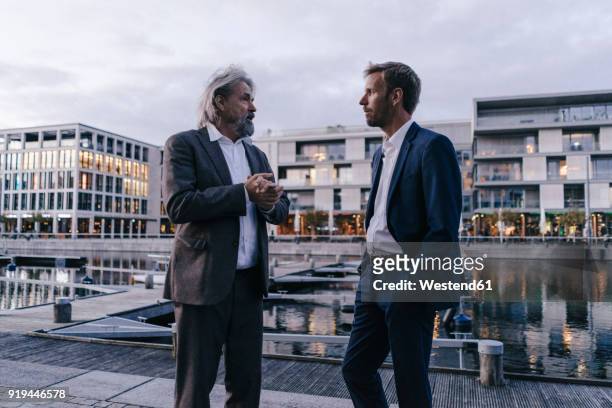 two businessmen talking at city harbor at dusk - dortmund city centre stock pictures, royalty-free photos & images