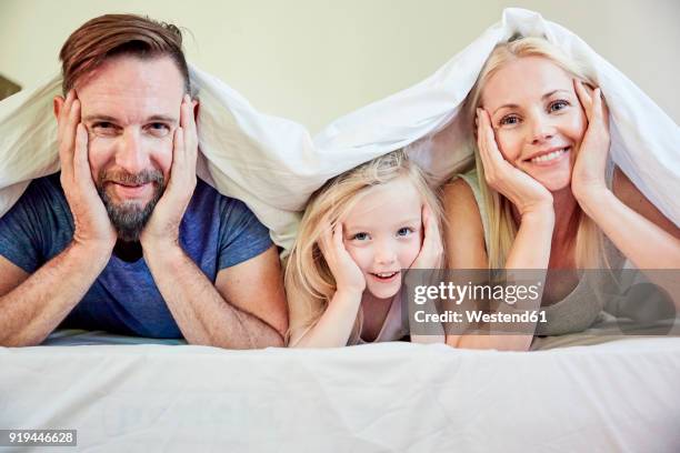portrait of happy family under blanket in bed - mom head in hands stock pictures, royalty-free photos & images
