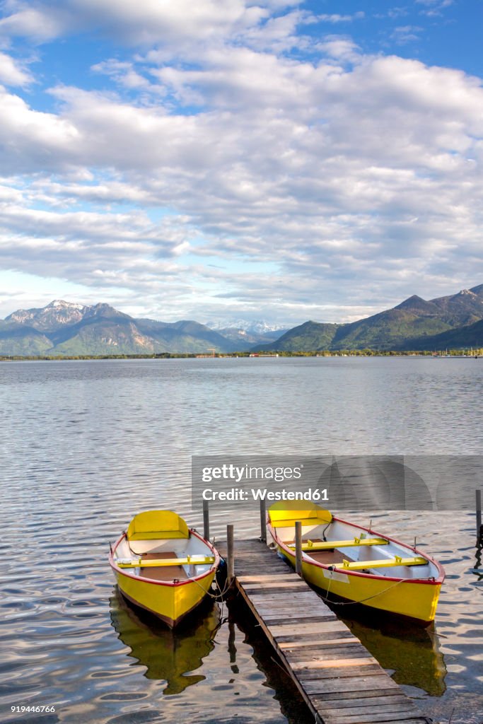 Germany, Bavaria, Chiemsee, Prien am Chiemsee, yellow rowing boats at boardwalk