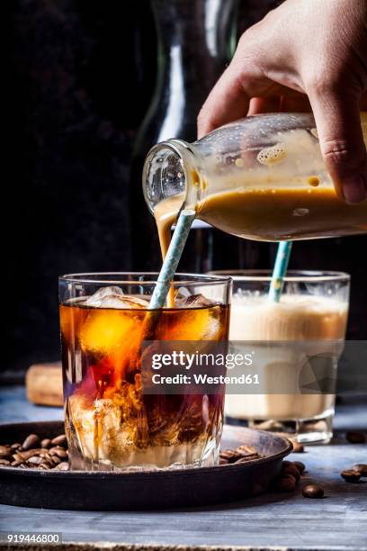 hand pouring homemade vanilla flavoured coffee creamer into a glas with iced coffee - glas bottle imagens e fotografias de stock