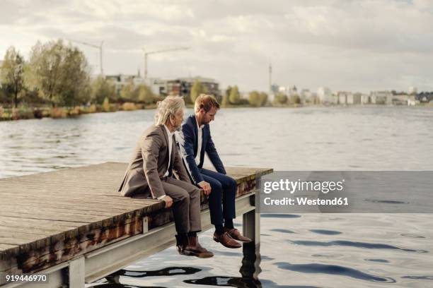 two businessmen sitting on jetty at a lake - successor stock pictures, royalty-free photos & images