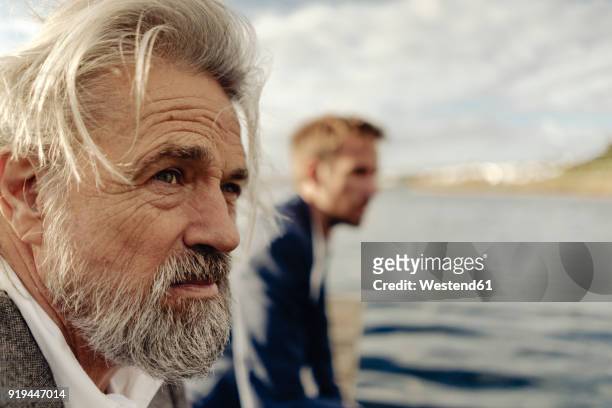 portrait of serious senior man at a lake with man in background - long jetty stock pictures, royalty-free photos & images