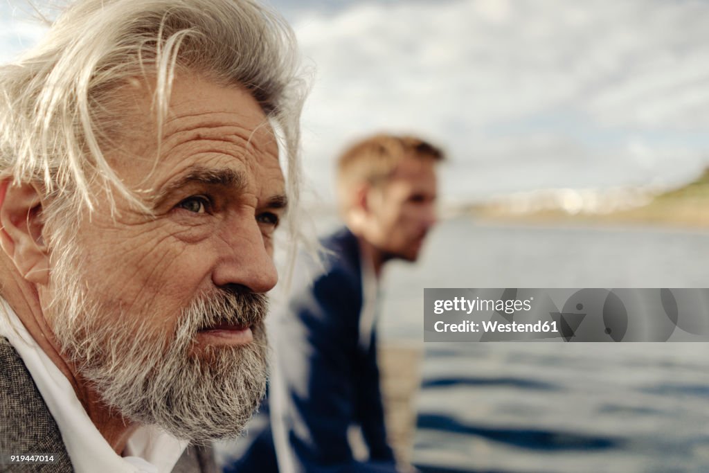 Portrait of serious senior man at a lake with man in background