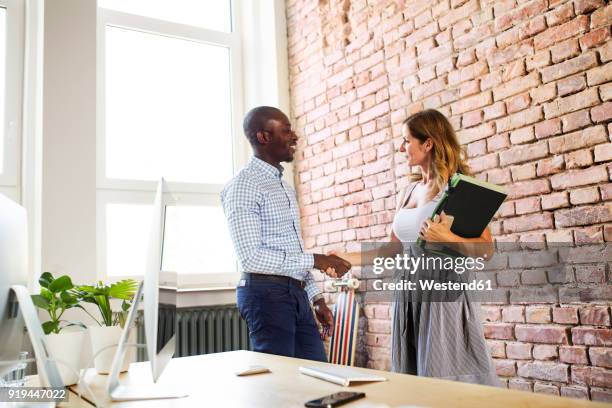 two colleagues shaking hands in office - african map stockfoto's en -beelden