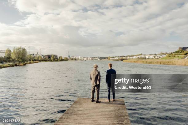 two businessmen standing on jetty at a lake - successor stockfoto's en -beelden