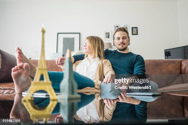 couple sitting on couch at home with model of eiffel tower and empire state building - paris manhattan stock pictures, royalty-free photos & images