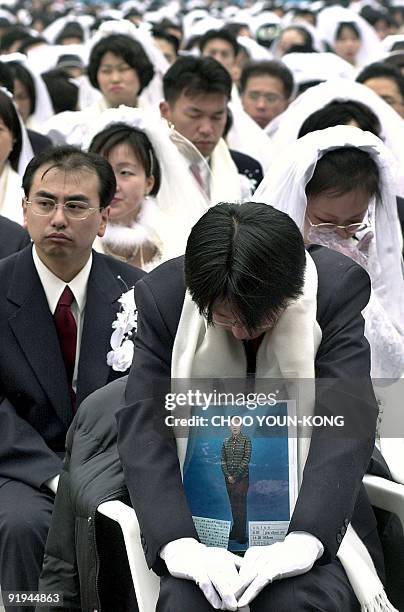 Japanese "Moonie" holding a portrait of his bride, who couldn't join in the mass wedding event, is overwhelmed during the ceremony given by the...