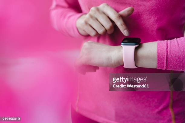 close-up of woman in pink sportswear adjusting her smartwatch - smart watch on wrist stock pictures, royalty-free photos & images