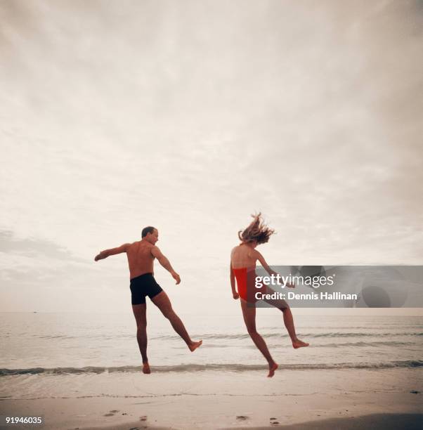 Young couple leaping into air at beach