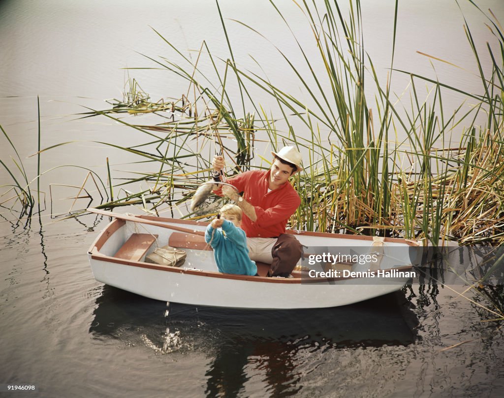 Father and son netting fish from rowboat