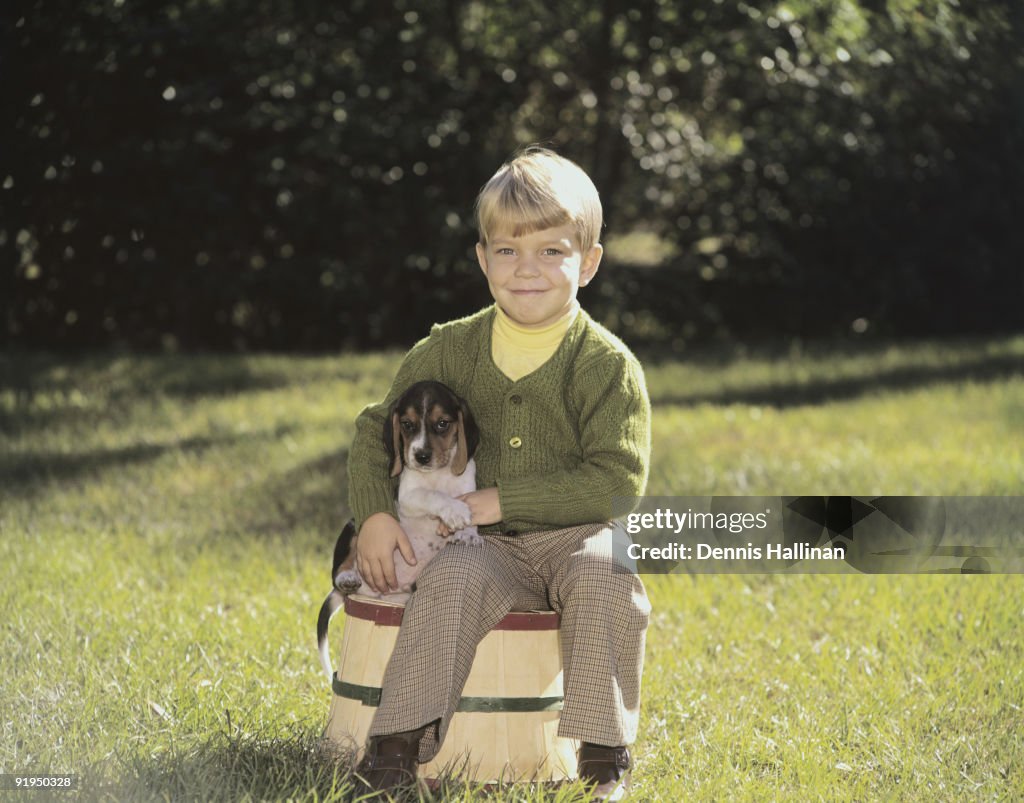 Small boy outdoors holding puppy