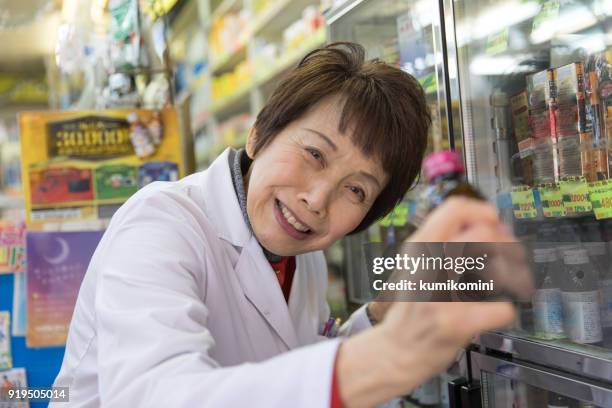 japanese chemist woman offering vitamin drink - powerfull stock pictures, royalty-free photos & images