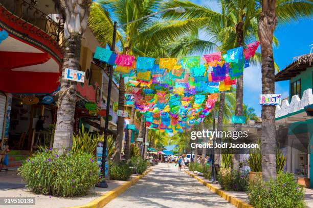 colorful flags over street in village of sayulita, mexico - sayulita stock pictures, royalty-free photos & images