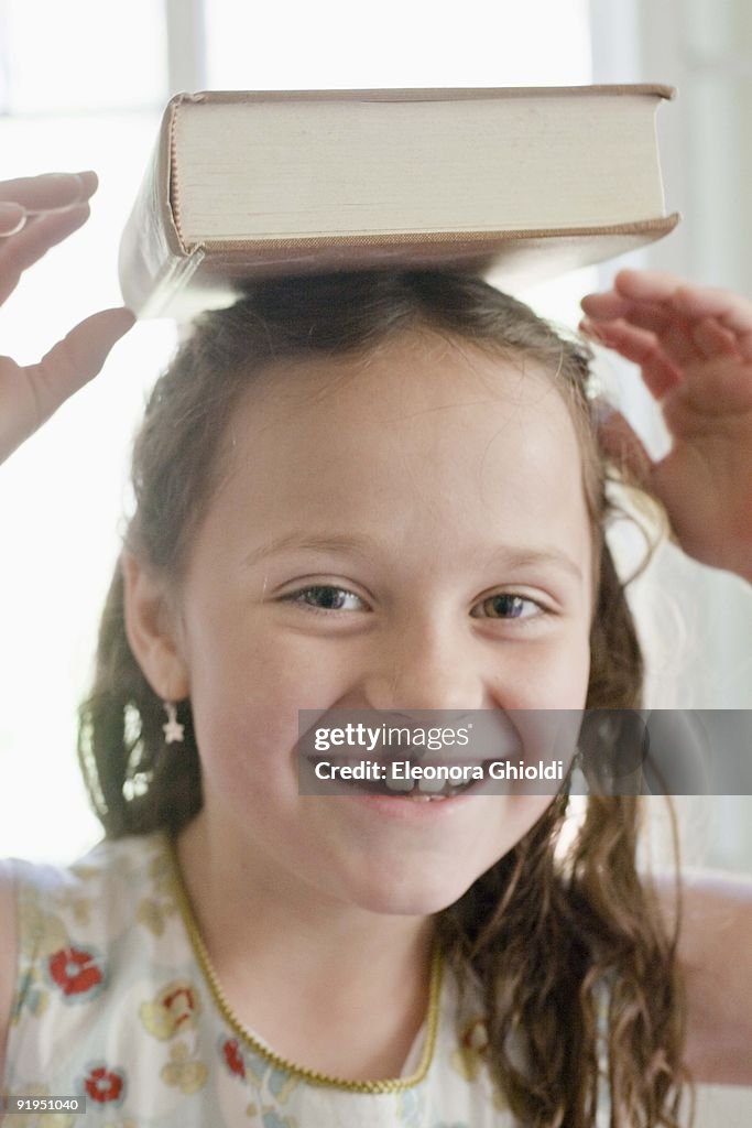 Girl with book on her head smiling