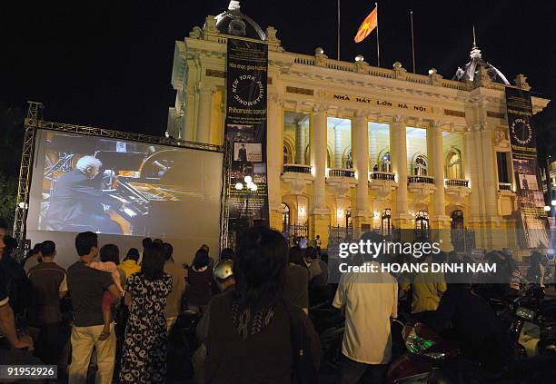 People watch piannist Emanuel Ax of the New York Philharmonic playing Beethoven's piano concerto No. 4 live broadcast on a large screen placed...