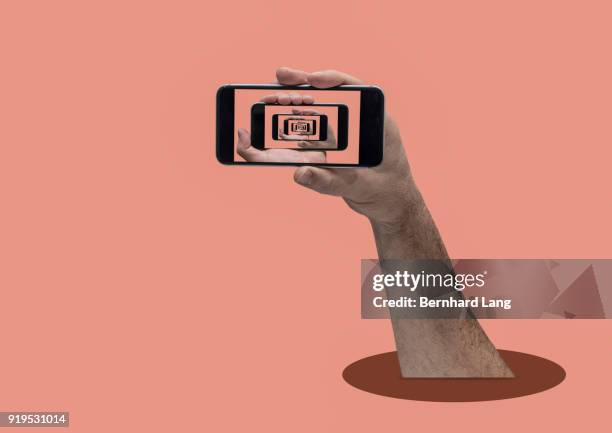 hand of man holding cell phone displaying itself endlessly - digital composite phone stock pictures, royalty-free photos & images