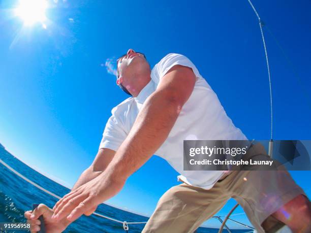 a skipper trimming a sail on board a yacht cruising in pittwater on the north shore from sydney, aus - pittwater stock pictures, royalty-free photos & images