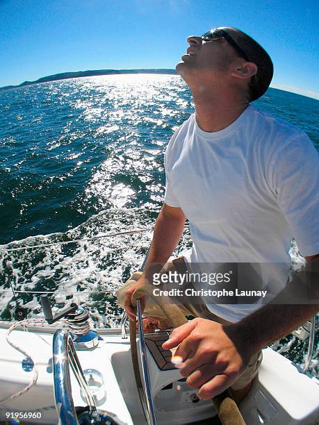 a skipper steering on board a yacht under blue skies while cruising in pittwater on the north shore  - pittwater stock pictures, royalty-free photos & images