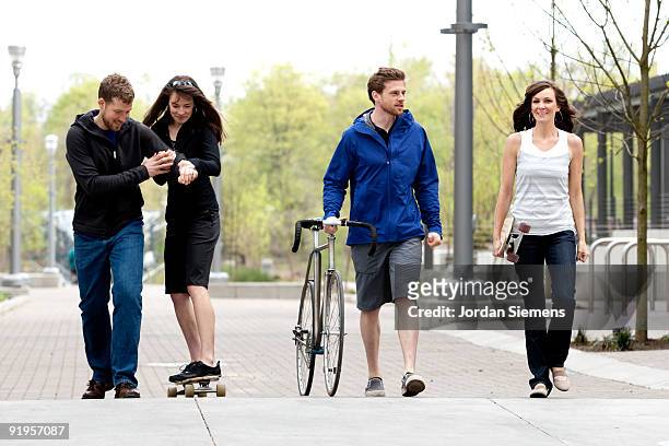 a group of friends having fun with a bike and a skateboard in the city. - newfriendship stock pictures, royalty-free photos & images