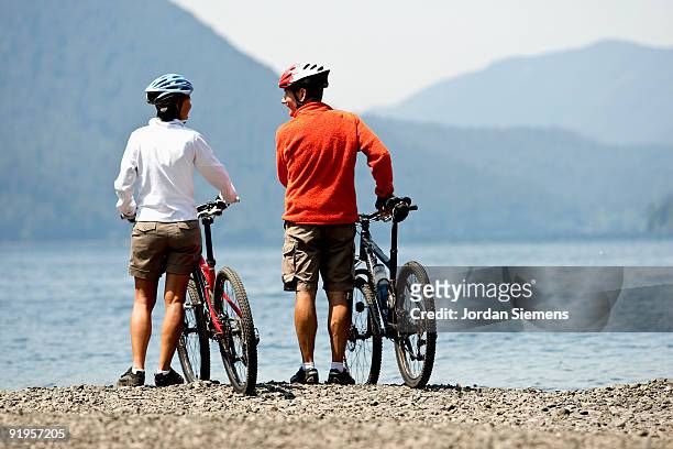 mountain bikers enjoying views of the lake and hillsides covered in trees. - lago crescent foto e immagini stock