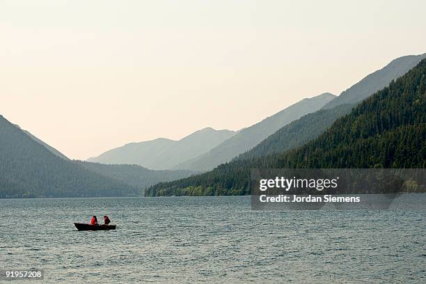 two people in a row boat on a deserted lake. - lago crescent foto e immagini stock