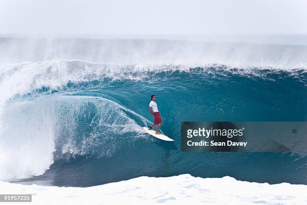 a young man surfing with a lot of skill and style at the pipeline, on the north shore of oahu, hawai - north shore oahu stock pictures, royalty-free photos & images