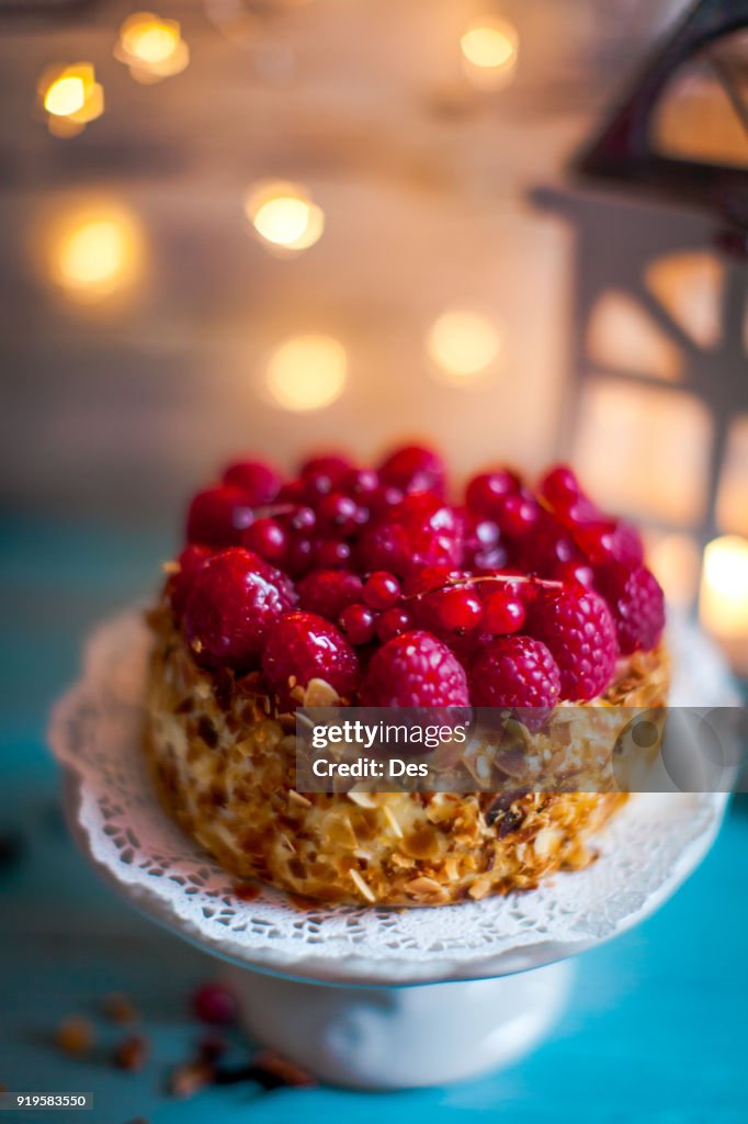 Sponge cake on a cake stand with fresh raspberries and redcurrants