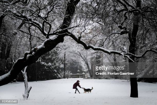 Woman plays with her dog on the snow-covered Maximiliansplatz on February 17, 2018 in Munich, Germany.