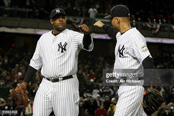 Sabathia of the New York Yankees walks off the field in the eighth inning and is congratulated by Derek Jeter during Game One of the ALCS against the...