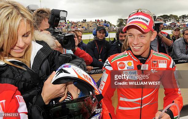 Australian MotoGP rider Casey Stoner smiles as he hands his helmet to his wife Adriana after claiming pole position on his Ducati for the Australian...