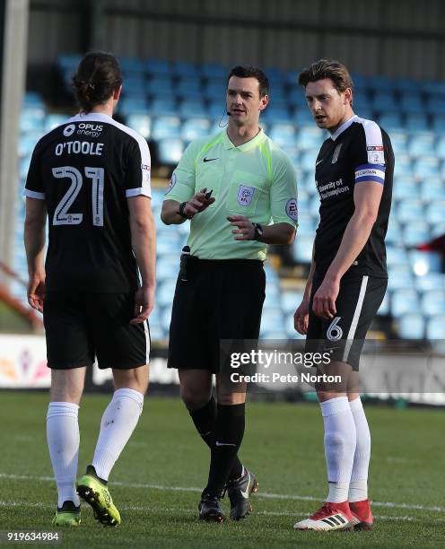 Referee Andrew Madley makes a point to Ash Taylor and John-Joe O'Toole of Northampton Town during the Sky Bet League One match between Scunthorpe...