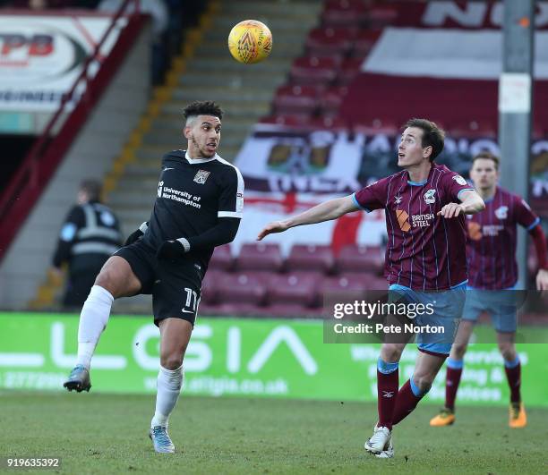 Daniel Powell of Northampton Town looks to the ball with Josh Morris of Scunthorpe United during the Sky Bet League One match between Scunthorpe...