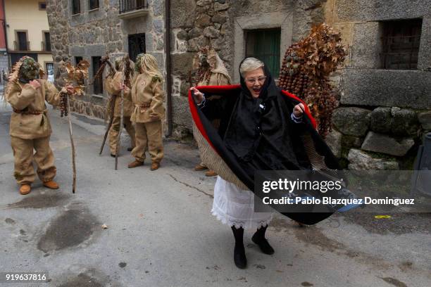 Woman wearing a traditional costume dances next to the 'Harramachos' during the traditional Navalacruz Carnival on February 17, 2018 in Navalacruz,...