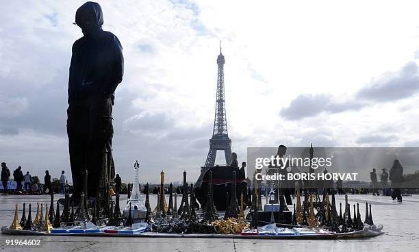 Souvenirs salesman waits for tourists, on the Esplanade du Trocadero, in front of the Eiffel tower on October 17, 2009 in Paris. AFP PHOTO BORIS...
