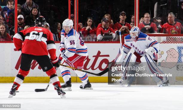 Making his NHL debut Brandon Halverson of the New York Rangers defends the net as team mate Nick Holden clears the puck and Mark Stone of the Ottawa...