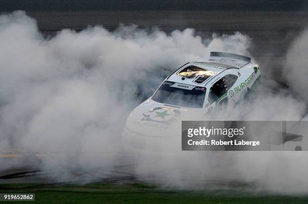 Tyler Reddick, driver of the BurgerFi Chevrolet, celebrates with a burnout after winning the NASCAR Xfinity Series PowerShares QQQ 300 at Daytona...