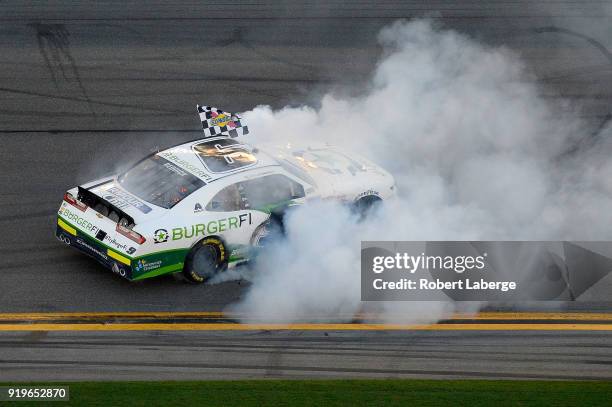 Tyler Reddick, driver of the BurgerFi Chevrolet, celebrates with a burnout after winning the NASCAR Xfinity Series PowerShares QQQ 300 at Daytona...