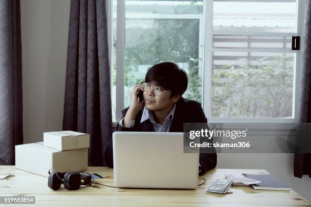 asian business man holding tablet for online shopping with laptop computer and with packaged to be shipped global - quitar fondo de imagen online fotografías e imágenes de stock