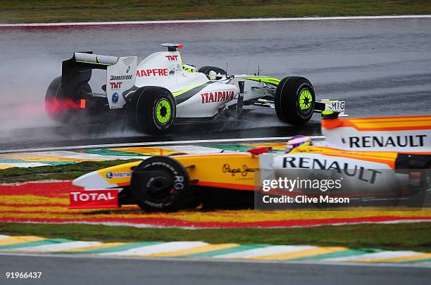 Jenson Button of Great Britain and Brawn GP drives by as Romain Grosjean of France and Renault spins in the rain affected final practice session...