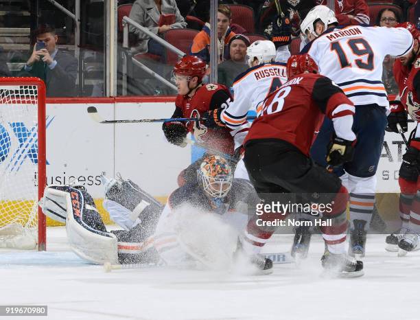 Goalie Cam Talbot of the Edmonton Oilers covers the puck as Christian Dvorak of the Arizona Coyotes battles with Kris Russell and Patrick Maroon of...