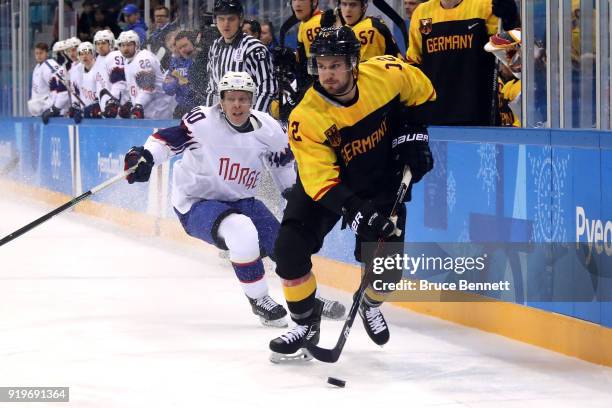 Brooks Macek of Germany controls the puck against Ken Andre Olimb of Norway in the first period during the Men's Ice Hockey Preliminary Round Group B...