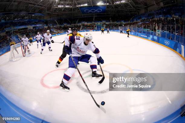 Niklas Roest of Norway controls the puck against Frank Mauer of Germany in the first period during the Men's Ice Hockey Preliminary Round Group B...