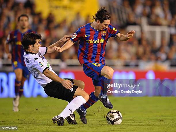 Lionel Messi of Barcelona is tackled by David Albelda of Valencia during the La Liga Match between Valencia and Barcelona at Estadio Mestalla on...