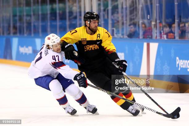 Alexander Bonsaksen of Norway competes for the puck with Marcus Kink of Germany in the first period during the Men's Ice Hockey Preliminary Round...