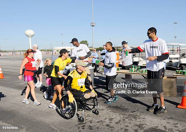 San Antonio Spurs players Antonio McDyess , Curtis Jerrells and Tim Duncan gives water to runners the during the Spurs Fast Break 5K on October 17,...