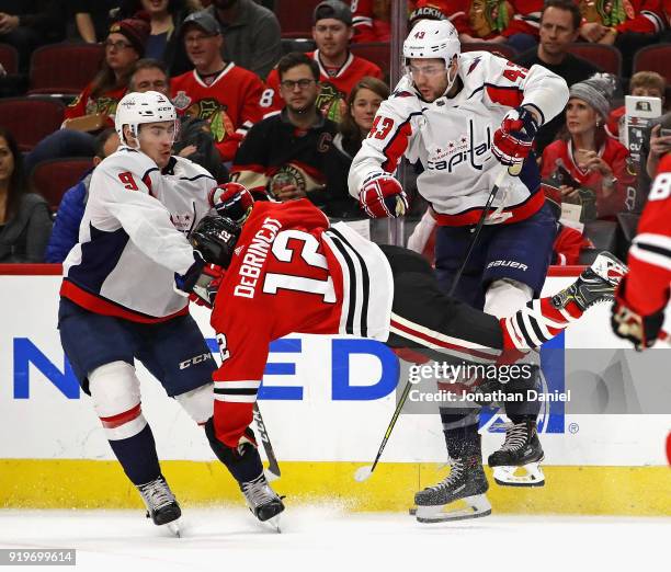 Alex DeBrincat of the Chicago Blackhawks collides with Tom Wilson and Dmitry Orlov of the Washington Capitals at the United Center on February 17,...