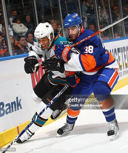 Jack Hillen of the New York Islanders hangs onto Manny Malhotra of the San Jose Sharks at the Nassau Coliseum on October 17, 2009 in Uniondale, New...